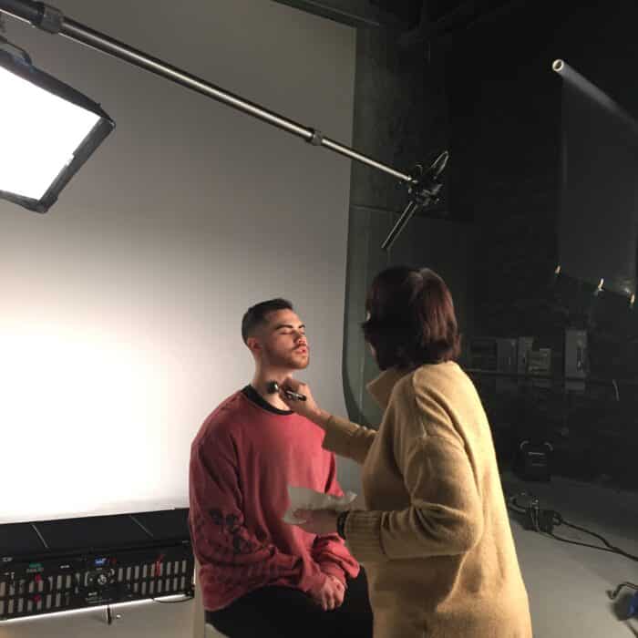 Make up artist working with and inteview subject in a video production