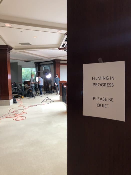 View of video production set with a sign that reads Fliming in Progress Please Be Quite