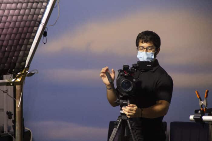 Cameraman checking the framing of a shot in front of a screen showing the sky